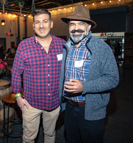 Two men stand in a low-lit brewpub